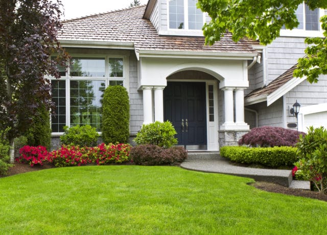 Exterior of a green home with a well maintained front yard.