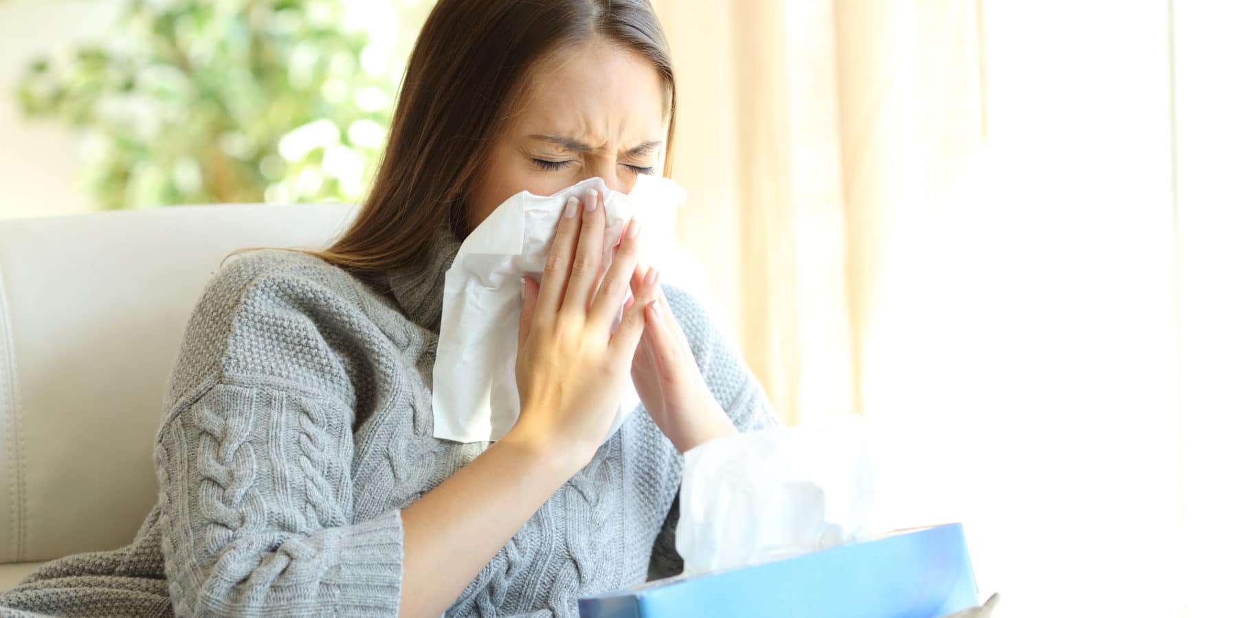 Woman blowing her nose due to a dust allergy.