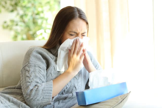 Woman blowing her nose due to a dust allergy.