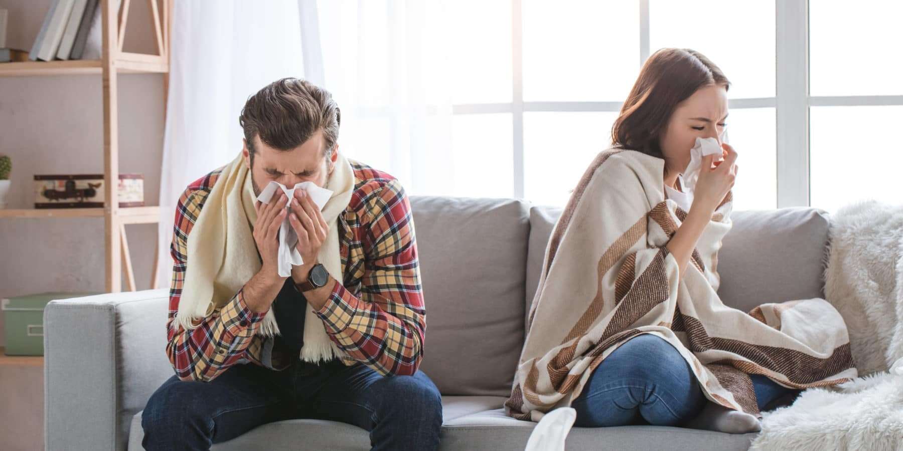 Young couple sitting on the couch together sick from mold sickness.