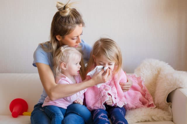 Mother of two little children helping her sick child